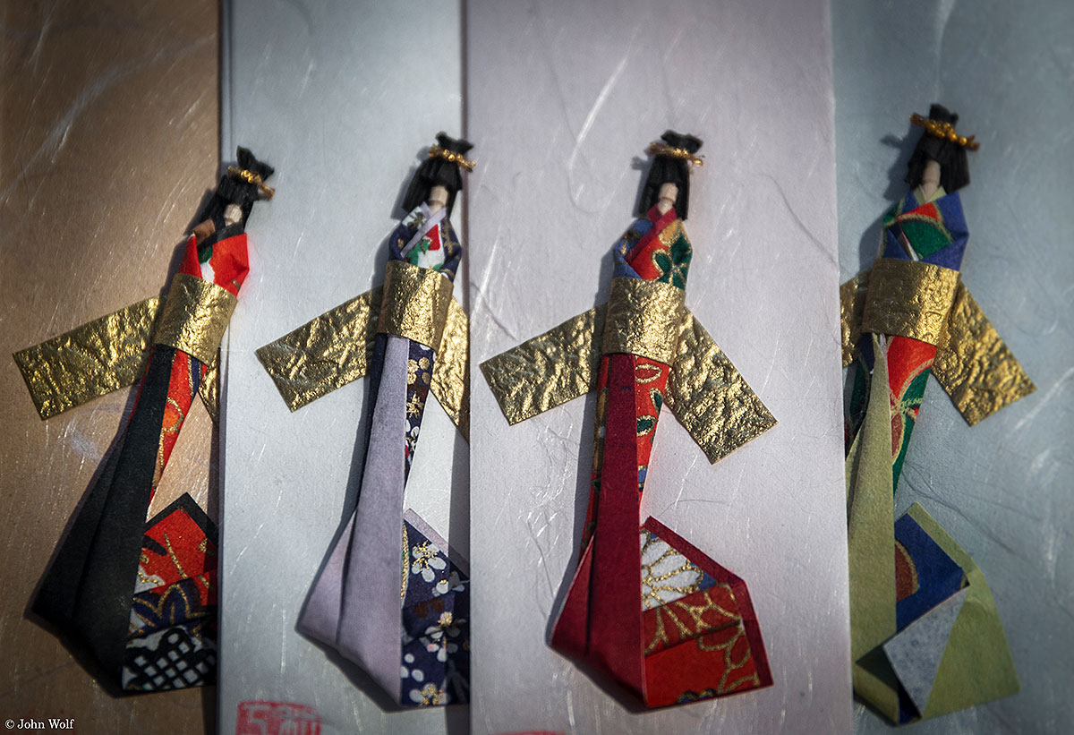 Bonecas japonesas sobre papéis de várias tonalidades.