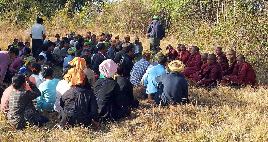 Aldeões e grupo de monges budistas na celebração dos rituais de um funeral numa aldeia de Myanmar.