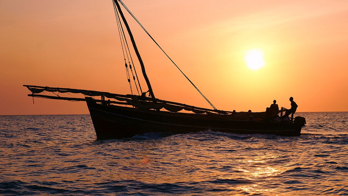 Dhow, o barco com velas em forma triangular típico do Oceano Indico, no caso junto à ilha de Zanzibar ao pôr-do-sol.