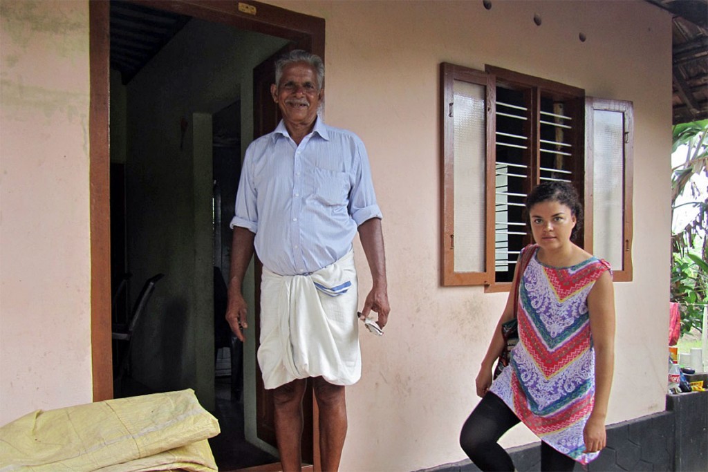 Homem indiano, vestido com um lungi, à entrada da sua casa em Alappuzha.