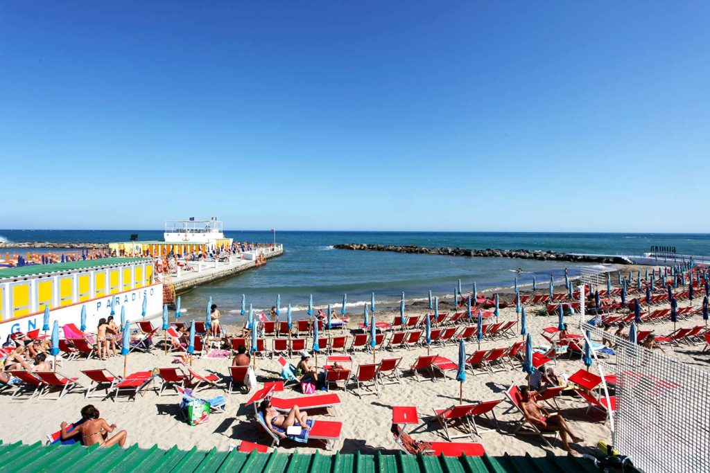 Praia "Spiaggia dei porti", repleta de cadeiras vermelhas, em São Remo, Itália