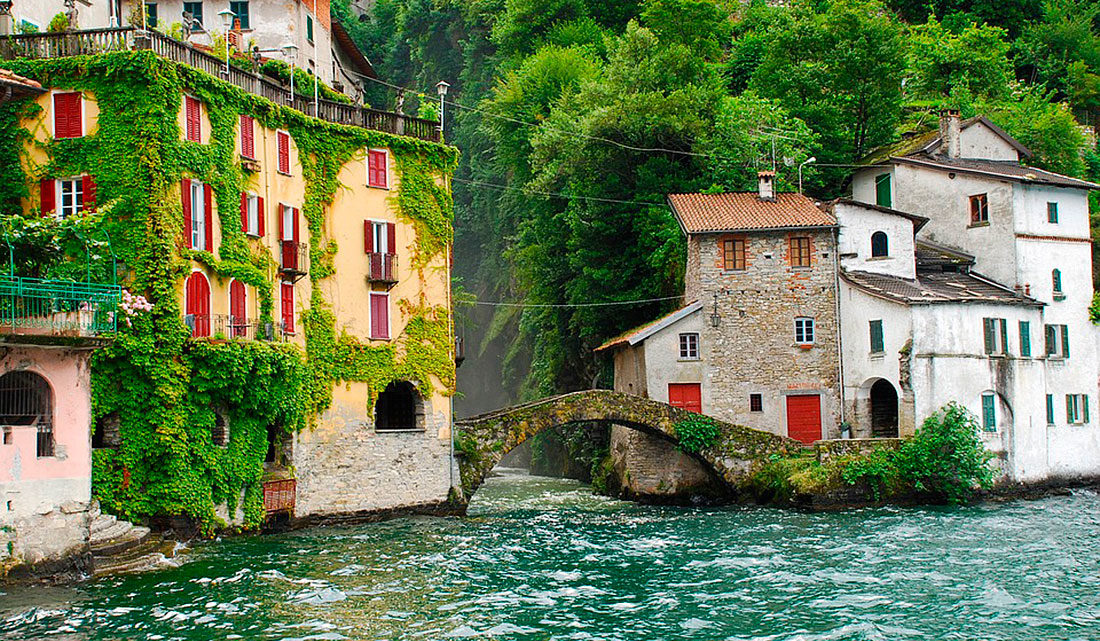Ponte e casario antigo, junto a zona muito verdejante, no Lago Como